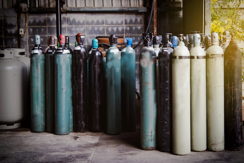Various used oxygen cylinders stored upright in a storage area.